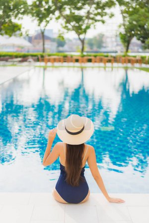 Téléchargez les photos : Portrait belle jeune femme asiatique se détendre sourire autour de la piscine extérieure dans la station hôtelière en voyage de vacances - en image libre de droit