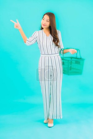 Photo for Portrait beautiful young asian woman with basket for shopping at supermarket on blue background - Royalty Free Image