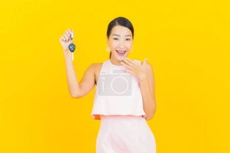 Foto de Retrato hermosa joven mujer asiática sonrisa con llave del coche sobre fondo de color amarillo - Imagen libre de derechos
