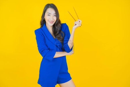Téléchargez les photos : Portrait belle jeune femme asiatique avec baguettes sur fond de couleur - en image libre de droit