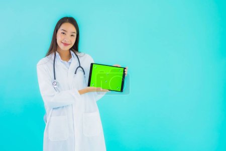 Téléchargez les photos : Portrait belle jeune femme asiatique médecin avec stéthoscope et tablette intelligente pour une utilisation à l'hôpital et la clinique sur fond bleu isolé - en image libre de droit