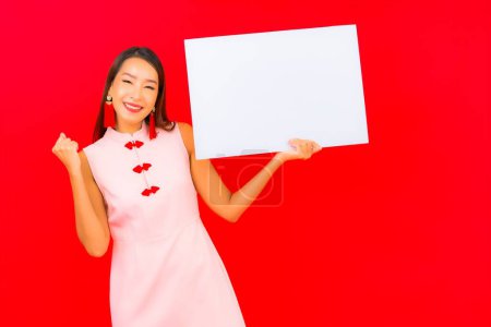 Téléchargez les photos : Portrait belle jeune asiatique femme montrer blanc vide panneau d'affichage sur fond rouge - en image libre de droit