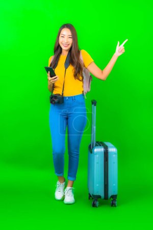 Foto de Retrato hermosa joven asiática mujer con cámara teléfono equipaje mapa listo para viajar sobre fondo verde - Imagen libre de derechos