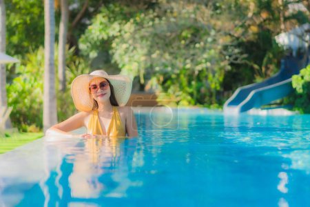 Téléchargez les photos : Portrait belle jeune femme asiatique sourire heureux se détendre autour de la piscine extérieure dans la station hôtelière pour les vacances de loisirs Voyage - en image libre de droit