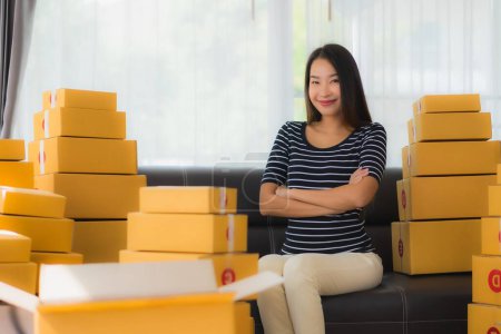 Téléchargez les photos : Portrait belle jeune femme asiatique avec emballage de boîte de colis en carton conteneur préparer pour l'expédition pour le client achats en ligne dans le salon - en image libre de droit
