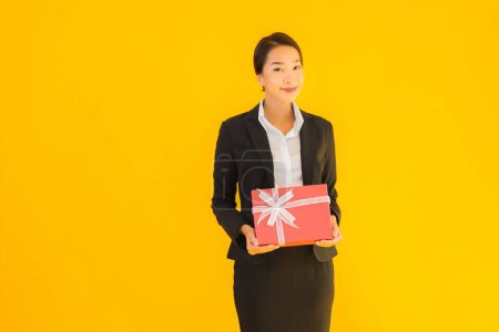 Photo for Portrait beautiful young asian woman show red gift box with happy smile on yellow isolated background - Royalty Free Image