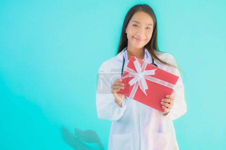 Foto de Retrato hermosa joven asiática médico mujer con caja de regalo en azul aislado fondo - Imagen libre de derechos