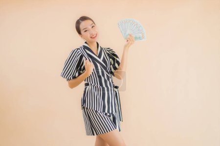 Téléchargez les photos : Portrait belle jeune femme asiatique avec de l'argent et de l'argent sur fond brun - en image libre de droit