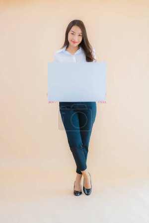 Foto de Retrato hermosa joven asiática mujer de negocios mostrar blanco cartelera vacía en fondo de color aislado - Imagen libre de derechos