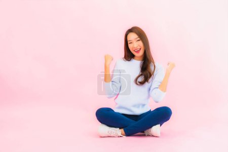 Foto de Retrato hermosa joven asiática mujer sentarse en el suelo con color rosa aislado fondo - Imagen libre de derechos