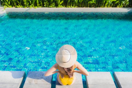 Téléchargez les photos : Portrait belle jeune femme asiatique se détendre sourire heureux autour de la piscine extérieure dans la station hôtelière pour les vacances de loisirs - en image libre de droit