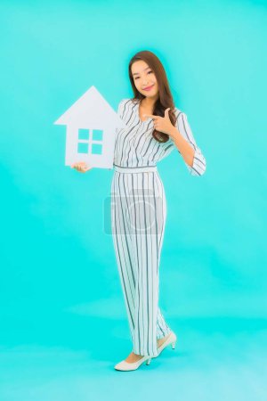 Foto de Retrato hermosa joven asiática mujer mostrar casa o casa signo sobre fondo azul - Imagen libre de derechos