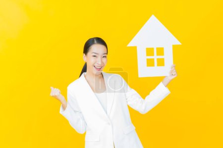Téléchargez les photos : Portrait belle jeune femme asiatique avec maison ou maison signe de papier sur fond de couleur - en image libre de droit