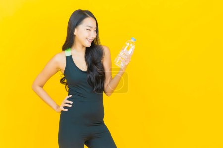 Foto de Retrato hermosa joven asiático mujer desgaste gimnasio traje listo para el ejercicio en amarillo color fondo - Imagen libre de derechos