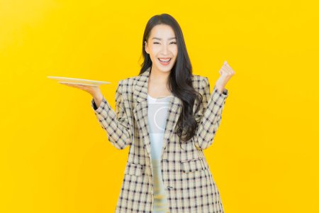 Foto de Retrato hermosa joven mujer asiática sonrisa con plato vacío en el fondo de color - Imagen libre de derechos