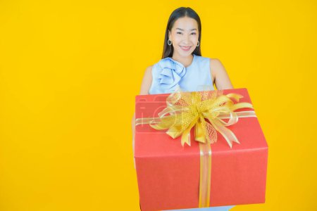 Foto de Retrato hermosa joven mujer asiática sonrisa con caja de regalo roja sobre fondo de color - Imagen libre de derechos