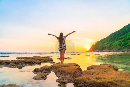 Photo for Portrait asian woman stand on the rock at sunset around beach sea ocean in travel vacation trip - Royalty Free Image