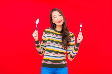 Photo for Portrait beautiful young asian woman ready to eat with spoon and fork on red background - Royalty Free Image