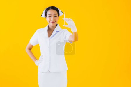 Foto de Retrato hermosa joven asiática mujer tailandesa enfermera usar guante en amarillo aislado fondo - Imagen libre de derechos