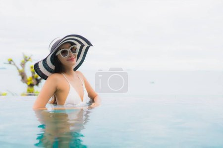 Foto de Retrato hermosa joven mujer asiática sonrisa relajarse y ocio alrededor de la piscina al aire libre en el complejo - Imagen libre de derechos