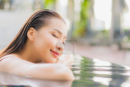 Foto de Retrato hermosa joven mujer asiática relajarse sonrisa alrededor de la piscina al aire libre en el complejo hotelero en viajes de vacaciones - Imagen libre de derechos