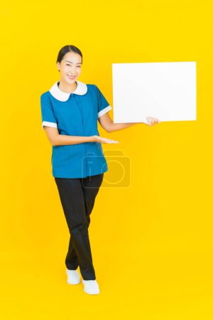 Photo for Portrait beautiful young asian woman maid and housekeeping smile with action on yellow color background - Royalty Free Image