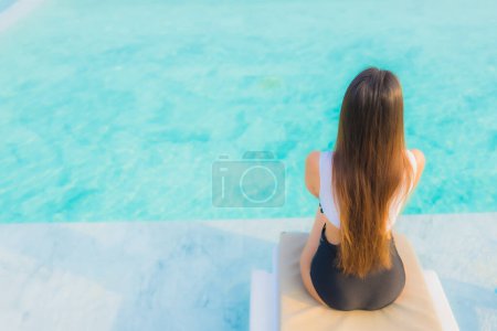Foto de Retrato hermosa joven mujer asiática feliz sonrisa relajarse alrededor de la piscina al aire libre en el complejo hotelero para vacaciones de viaje - Imagen libre de derechos