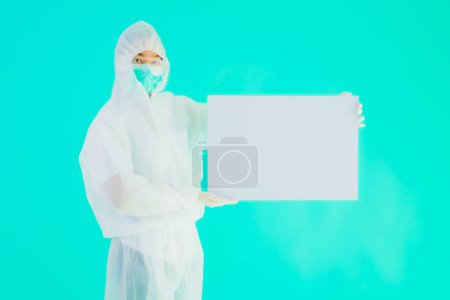 Photo for Portrait beautiful young asian doctor woman wear ppe or  personal protective equipment for protect from coronavirus or covid19 with empty card white board on blue isolated background - Royalty Free Image