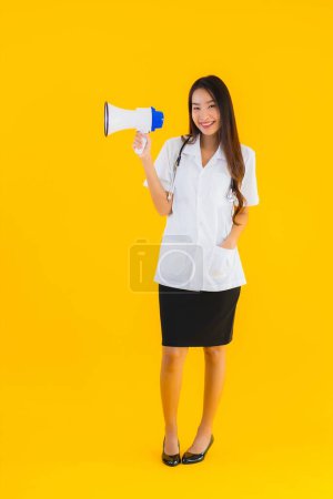 Photo for Portrait beautiful young asian doctor woman use megaphone on yellow isolated background - Royalty Free Image