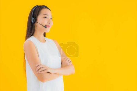 Foto de Retrato hermosa joven asiática mujer callcenter para la asistencia en amarillo aislado fondo - Imagen libre de derechos
