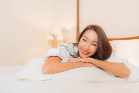 Téléchargez les photos : Portrait belle jeune femme asiatique sourire détendre loisirs sur lit dans chambre à coucher intérieur - en image libre de droit