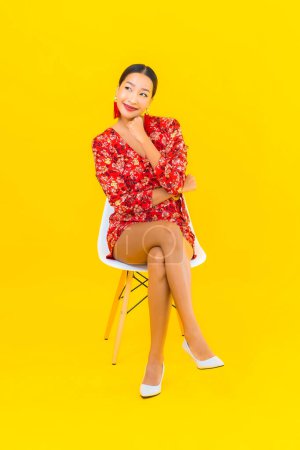 Téléchargez les photos : Portrait belle jeune femme asiatique avec téléphone mobile intelligent et s'asseoir sur la chaise - en image libre de droit