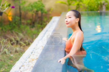 Téléchargez les photos : Portrait belle jeune femme asiatique profiter de se détendre autour de la piscine pour des vacances de loisirs - en image libre de droit