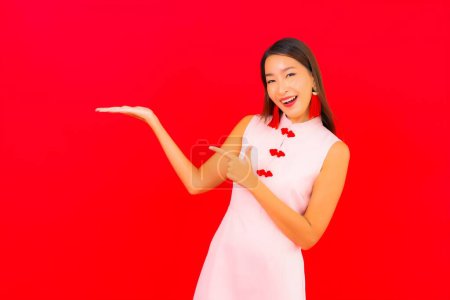 Foto de Retrato hermosa joven mujer asiática desgaste chino nuevo año ropa sobre fondo rojo - Imagen libre de derechos