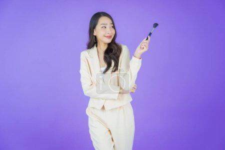 Téléchargez les photos : Portrait belle jeune femme asiatique avec maquillage pinceau cosmétique sur fond de couleur - en image libre de droit
