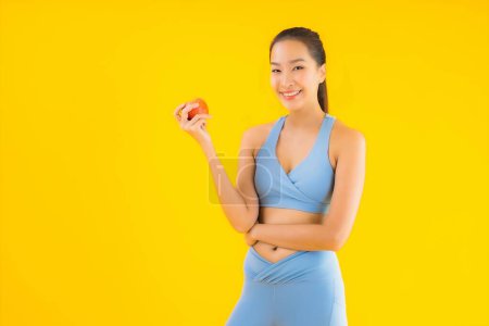 Foto de Retrato hermosa joven mujer asiática usar ropa deportiva listo para el ejercicio con fruta de manzana aislado fondo - Imagen libre de derechos