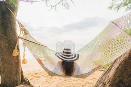 Téléchargez les photos : Portrait belle jeune femme asiatique se détendre sur hamac autour de la plage mer océan pour les loisirs en vacances - en image libre de droit