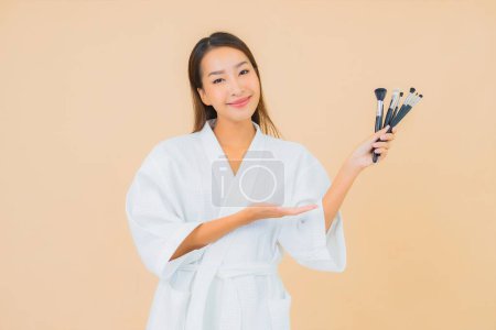 Photo for Portrait beautiful young asian woman with makeup brush on color isolated background - Royalty Free Image