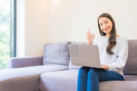 Photo for Portrait beautiful young asian woman use laptop for working in living room - Royalty Free Image