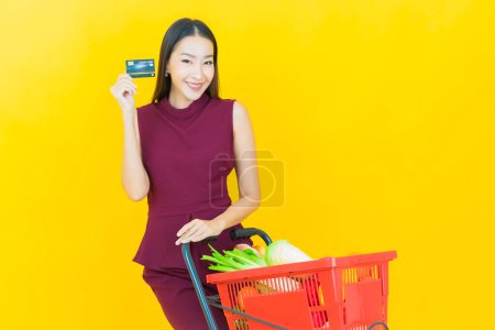 Foto de Retrato hermosa joven asiática mujer sonrisa con cesta de supermercado en color de fondo - Imagen libre de derechos