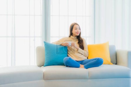 Photo for Portrait beautiful young asian woman with coffee cup on sofa in living room interior - Royalty Free Image