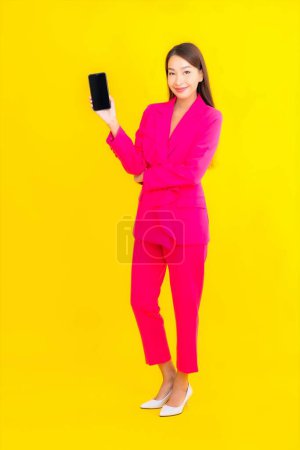 Photo for Portrait beautiful young asian woman use smart mobile phone on yellow color isolated background - Royalty Free Image