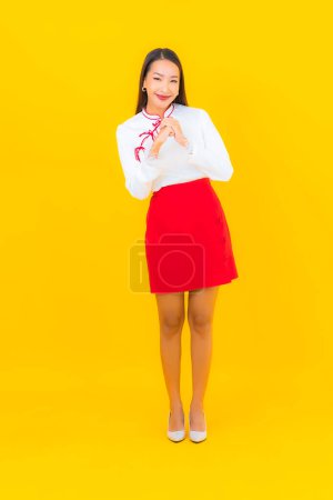Foto de Retrato hermosa joven mujer asiática sonrisa en acción sobre fondo amarillo - Imagen libre de derechos