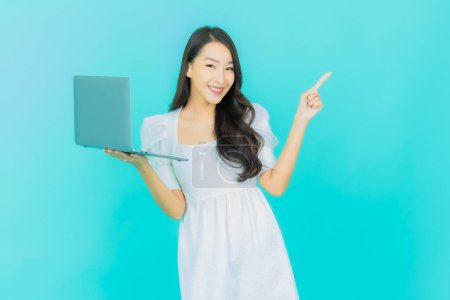 Téléchargez les photos : Portrait belle jeune femme asiatique sourire avec ordinateur portable sur fond isolé - en image libre de droit