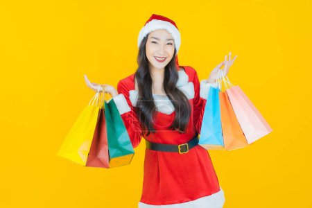 Foto de Retrato hermosa joven mujer asiática usar traje de navidad con bolsa de compras en el fondo de color - Imagen libre de derechos