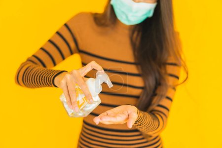 Photo for Portrait beautiful young asian woman with mask alcohol spray and gel bottle in her hand for protect from coronavirus or covid19 on yellow isolated background - Royalty Free Image
