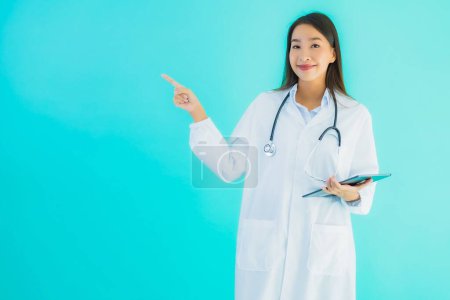 Foto de Retrato hermosa joven asiática médico mujer con estetoscopio y tableta inteligente para su uso en el hospital y la clínica sobre fondo aislado azul - Imagen libre de derechos