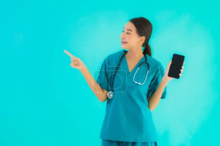 Photo for Portrait beautiful young asian doctor woman show smart mobile phone on blue isolated background - Royalty Free Image
