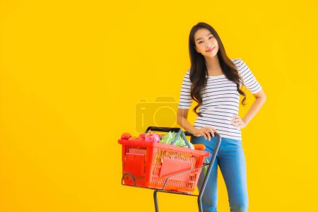 Photo for Portrait beautiful young asian woman shopping grocery from supermarket and cart on yellow isolated background - Royalty Free Image
