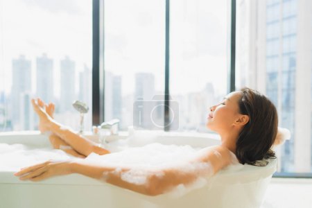 Téléchargez les photos : Portrait belle jeune femme asiatique se détendre et de loisirs dans la décoration de la baignoire dans la salle de bain intérieure - en image libre de droit